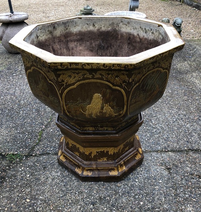 A large octagonal Japanese glazed terracotta garden urn, decorated with panels of animals in