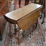 A Georgian oak drop leaf dining table with opposing end drawers, raised on turned gateleg action