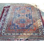 An antique worn Caucasian rug with a pair of red geometric medallions on blue ground within