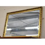 A rectangular bevelled edge wall mirror in gilt foliate frame