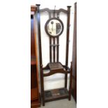 An early 20th century oak hall stand with a circular bevelled mirror over a glove box, umbrella