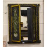 An ethnic bevelled edge wall mirror enclosed by black and foliate paint decorated doors and frame