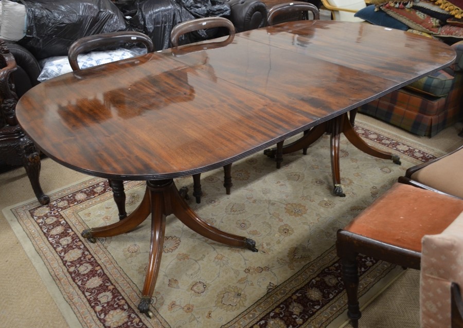 A Regency style twin pedestal mahogany dining table with single central leaf, turned columns and out