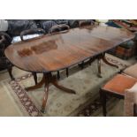 A Regency style twin pedestal mahogany dining table with single central leaf, turned columns and out