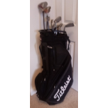 A Titleist golf bag containing three taylormade woods, nine wilson irons and a putter