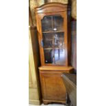 A burr walnut veneer floor standing corner cabinet with glazed door over panelled cupboard door