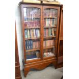 A stained pine bookcase on stand with a pair of glazed doors enclosing four adjustable shelves