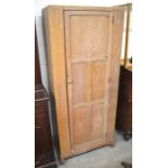 A limed oak hall cupboard with single panelled door enclosing a shelf and pull out hanging rail,