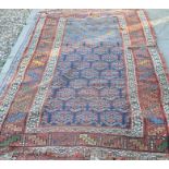 An antique worn Caucasian rug with repeating floral design on navy ground, navy border with stylised