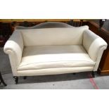 An Edwardian two seater settee with arched back and scroll arms in cream upholstery raised on shaped