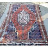 An old northwest Persian worn rug, the ivory central panel on red ground filled with stylised floral