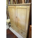 An old pine hall cupboard with a pair of panelled doors enclosing shelves over a single drawer