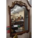 A large wall mirror with gilded shaped top and foliate decoration