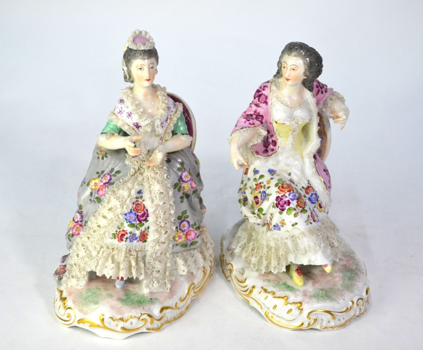 A pair of 19th century Berlin porcelain seated ladies with floral painted dresses and lacy