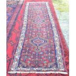 A Persian Tabriz runner with three geometric medallions on red ground with decorative floral