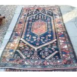 A Persian Hamadan rug with stylised rosettes on navy ground within a terracotta leaf border 222 x
