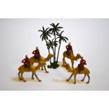 A set of four die cast toy camels and soldiers with palm trees, possiby Britains but unmarked, circa
