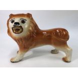 A Victorian Staffordshire model of a standing lion with glass eyes, 24.5 cm high x 33 cm