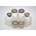 Three pairs of Victorian cut glass toilet bottles and jars with chased and engraved silver tops,