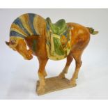 A Chinese glazed figure of a caparisoned horse in the Tang Dynasty style; the head leaning downwards