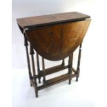 An antique cross-banded walnut butterfly veneered drop-leaf occasional table, raised on a slender