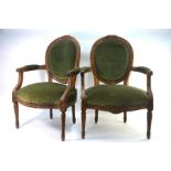 A pair of antique French salon elbow chairs, the carved frames with green fabric back panel and