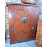 A red and gilt lacquered, Chinese cupboard decorated with groups of figures in apparently