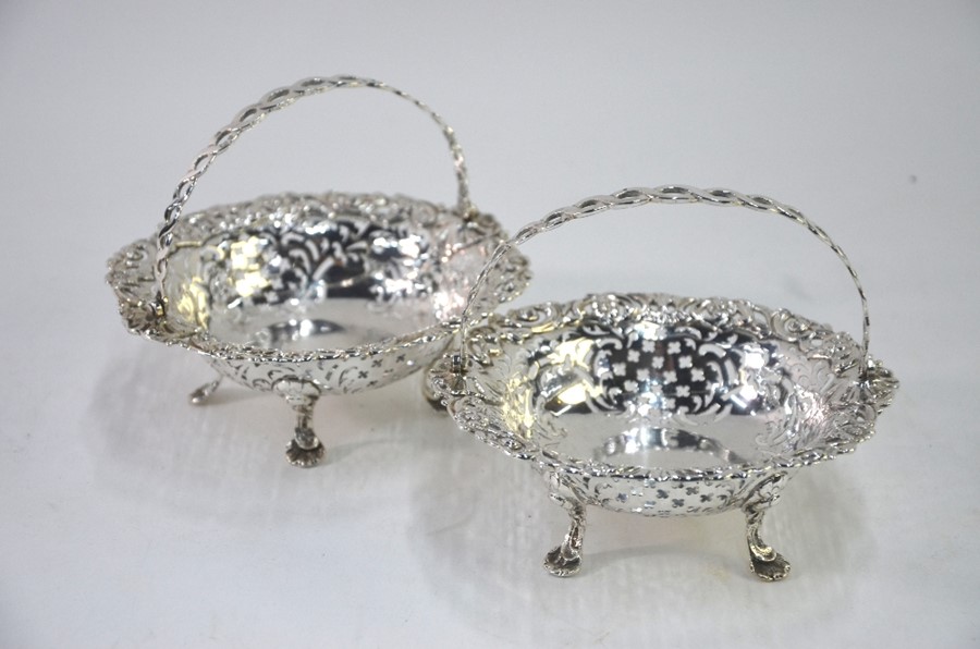 A pair of late Victorian pierced silver bonbon baskets with guilloche swing handles, on lion-mask