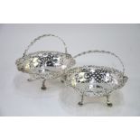 A pair of late Victorian pierced silver bonbon baskets with guilloche swing handles, on lion-mask