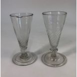 Two 18th century short ale glasses, each with a part wrythen bowl, knopped stem and folded foot,