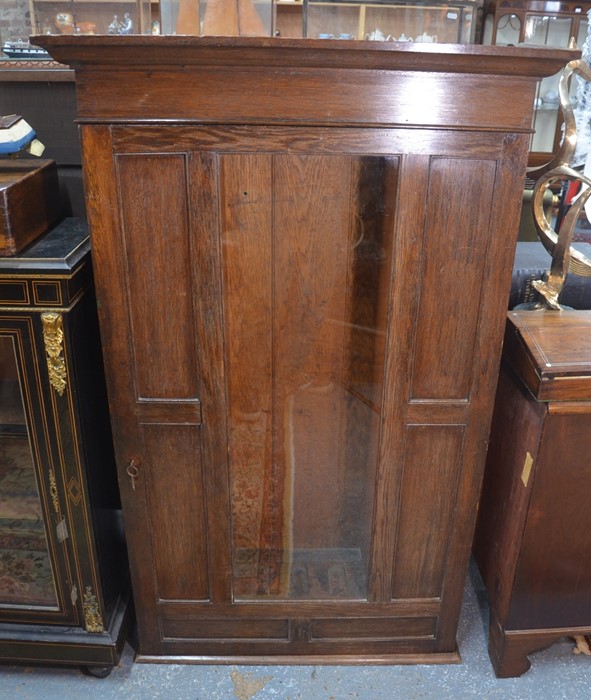 An Arts & Crafts period wall hanging oak gun cabinet, the single door centred by a glazed panel