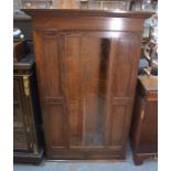 An Arts & Crafts period wall hanging oak gun cabinet, the single door centred by a glazed panel