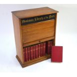 An oak table-top bookcase with tambour fall-front 'Miniature library of the Poets', containing a set