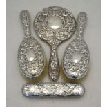 An embossed silver-back three piece brush set including hand mirror, Birmingham 1958 to/w a silver-