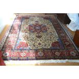 A Persian Tabriz carpet with large red floral motif on a cream field decorated with scrolling