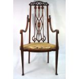 An Art Nouveau inlaid walnut elbow chair, the pierced fret cut crest rail over a conforming vertical