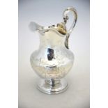 A Victorian Irish silver baluster milk jug with scroll handle and engraved rococo decoration, on