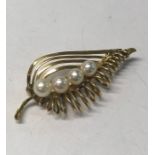 A contemporary yellow metal open work leaf brooch set with four graduated cultured pearls to central