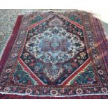An antique Persian Mahal rug with a large central ivory medallion on a navy field filled with
