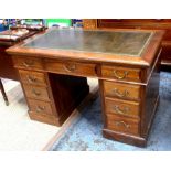 An Edwardian walnut twin pedestal desk, the top with tooled leather surface over an arrangement of