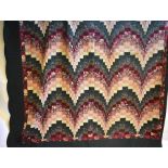 A vintage American Amish hand-sewn patchwork quilt in hues of burgundy and dark green with green