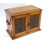 A Victorian oak smoker's cabinet with hinged top and carved panel doors enclosing fitted drawers,