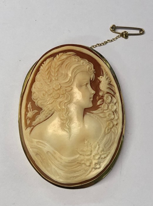 A large carved shell cameo featuring lady with ornate hair, garland of flowers and winged dove,