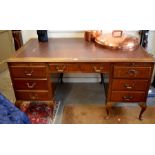 Early 20th century mahogany desk with gilt tooled leather top over fitted slides and seven drawers