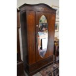 An inlaid mahogany Sheraton style wardrobe with bevelled oval mirrored door over a single drawer