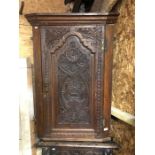 An antique carved oak hanging corner cupboard