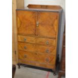 A 1950's walnut cocktail cabinet with two doors over three drawers raised on short cabriole supports