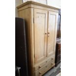 A French pine wardrobe with panelled doors enclosing a hanging rail over two long drawers raised