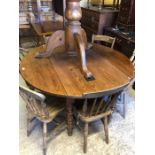An old French pine drop leaf dining table raised on turned supports to castors