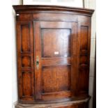 A Georgian oak hanging corner cabinet with single door enclosing two shelves